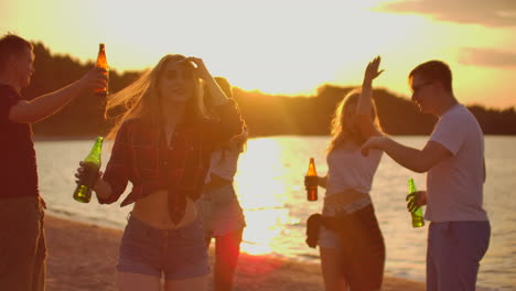 The-young-female-with-blonde-hair-is-dancing-with-slim-figure-on-the-open-air-party-with-beer.-She-spins-in-dance-to-the-music-and-enjoying-beach-party-with-the-best-friends-in-the-good-mood.